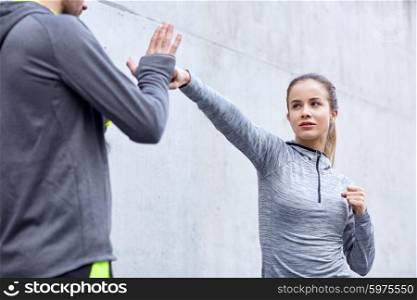 fitness, sport, martial arts, self-defense and people concept - woman with personal trainer working out strike outdoors