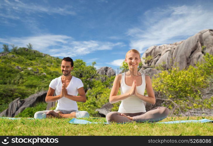 fitness, sport, meditation and people concept - happy couple doing yoga and meditating outdoors over natural background. happy couple doing yoga and meditating outdoors