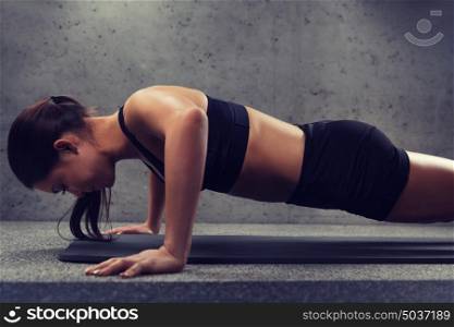 fitness, sport, people and exercising concept - woman doing push-ups in gym. woman doing push-ups in gym
