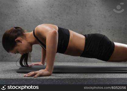 fitness, sport, people and exercising concept - woman doing push-ups in gym