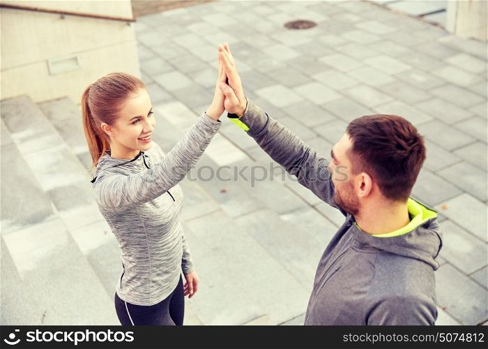 fitness, sport, people and gesture concept - smiling couple making high five on city street. smiling couple making high five on city street