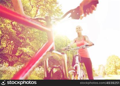 fitness, sport, people and healthy lifestyle concept - close up of happy couple riding bicycle outdoors at summer. close up of happy couple riding bicycle outdoors