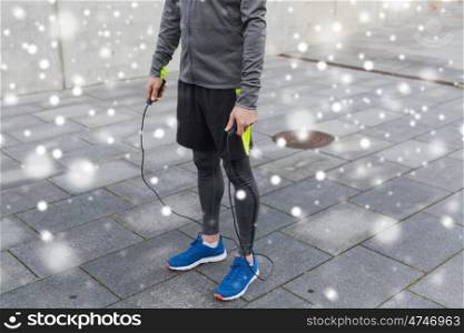 fitness, sport, people and healthy lifestyle concept - close up of man exercising with jump-rope over snow