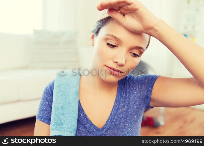 fitness, sport, people and healthy lifestyle concept - close up of tired woman with towel wiping sweat after exercising at home. close up of tired woman after workout at home
