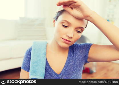 fitness, sport, people and healthy lifestyle concept - close up of tired woman with towel wiping sweat after exercising at home. close up of tired woman after workout at home