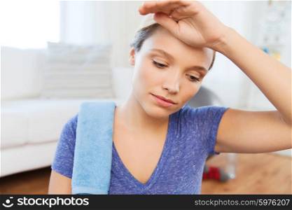 fitness, sport, people and healthy lifestyle concept - close up of tired woman with towel wiping sweat after exercising at home