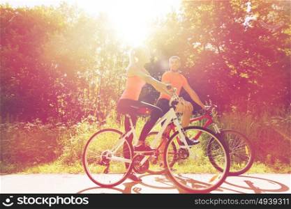 fitness, sport, people and healthy lifestyle concept - happy couple riding bicycle outdoors at summer. happy couple riding bicycle outdoors
