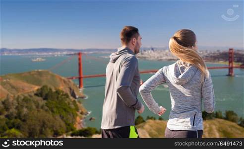 fitness, sport, people and healthy lifestyle concept - happy couple running over golden gate bridge in san francisco bay background. happy couple running over golden gate bridge. happy couple running over golden gate bridge