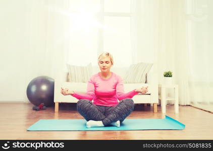 fitness, sport, people and healthy lifestyle concept - happy plus size woman stretching leg on mat at home. happy woman stretching leg on mat at home