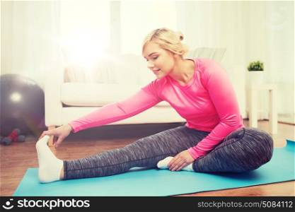fitness, sport, people and healthy lifestyle concept - happy plus size woman stretching leg on mat at home. happy woman stretching leg on mat at home. happy woman stretching leg on mat at home