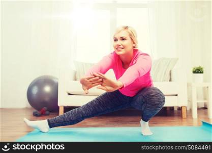 fitness, sport, people and healthy lifestyle concept - happy plus size woman stretching leg on mat at home. happy woman stretching leg on mat at home. happy woman stretching leg on mat at home