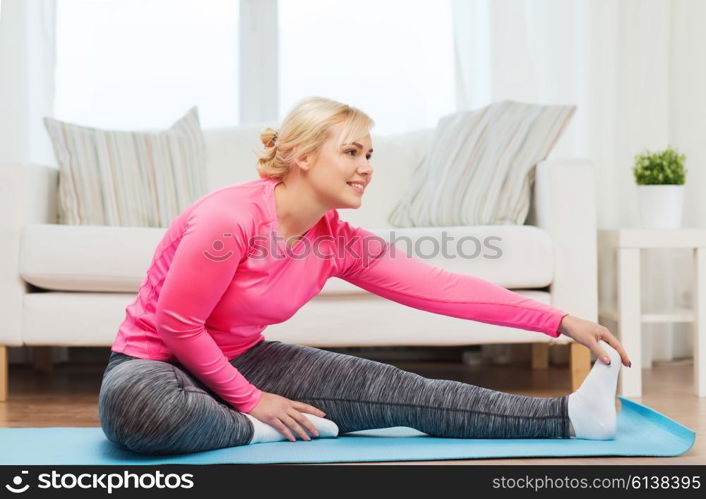 fitness, sport, people and healthy lifestyle concept - happy plus size woman stretching leg on mat at home