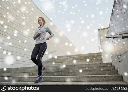 fitness, sport, people and healthy lifestyle concept - happy sporty woman running downstairs in city over snow