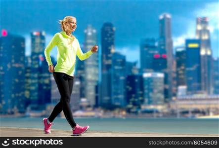fitness, sport, people and healthy lifestyle concept - happy woman jogging over city street background