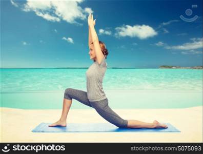 fitness, sport, people and healthy lifestyle concept - happy woman making yoga in low lunge pose on mat over sea and sky background. happy woman making yoga in low lunge on mat