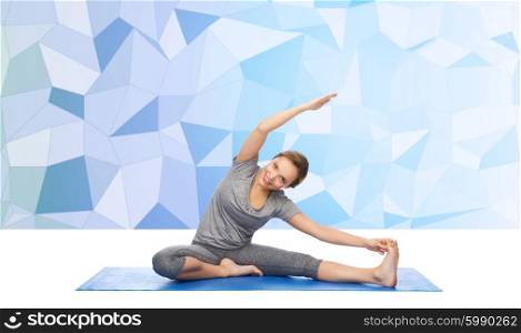 fitness, sport, people and healthy lifestyle concept - happy woman making yoga and stretching on mat over blue polygonal background