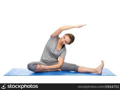 fitness, sport, people and healthy lifestyle concept - happy woman making yoga and stretching on mat