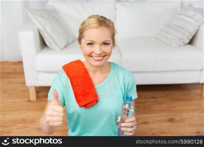 fitness, sport, people and healthy lifestyle concept - happy woman with bottle of water after exercising at home and showing thumbs up
