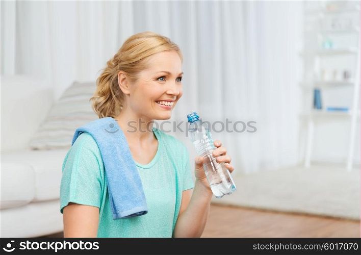 fitness, sport, people and healthy lifestyle concept - happy woman with bottle of water drinking after exercising at home
