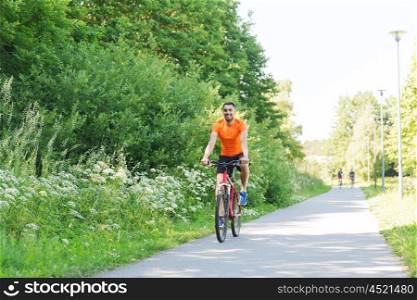 fitness, sport, people and healthy lifestyle concept - happy young man riding bicycle outdoors