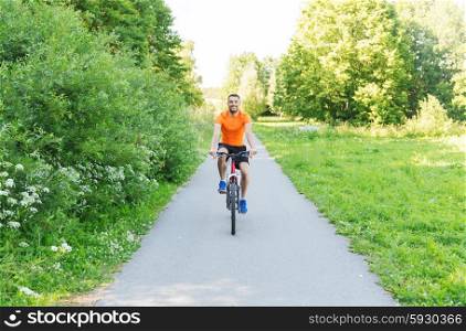 fitness, sport, people and healthy lifestyle concept - happy young man riding bicycle outdoors