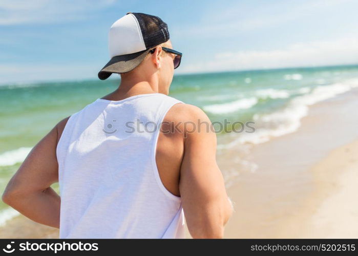 fitness, sport, people and healthy lifestyle concept - happy young man running along summer beach. happy man running along summer beach