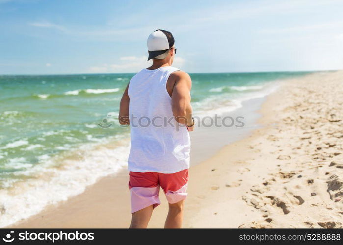 fitness, sport, people and healthy lifestyle concept - happy young man running along summer beach. happy man running along summer beach