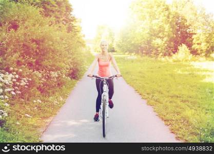 fitness, sport, people and healthy lifestyle concept - happy young woman riding bicycle outdoors. happy young woman riding bicycle outdoors