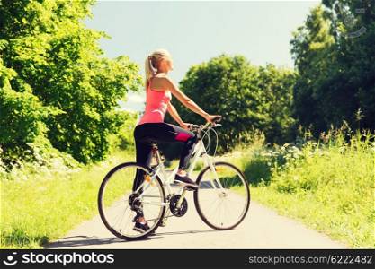fitness, sport, people and healthy lifestyle concept - happy young woman riding bicycle outdoors