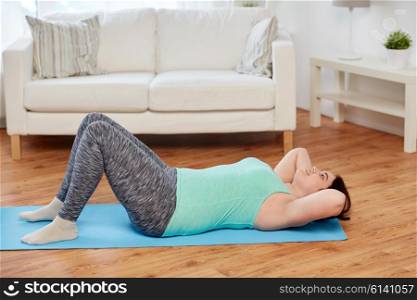 fitness, sport, people and healthy lifestyle concept - plus size young woman exercising on mat at home