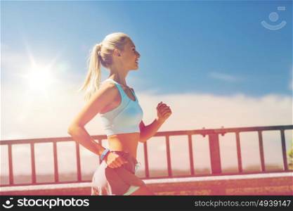 fitness, sport, people and healthy lifestyle concept - smiling young woman with heart rate watch running outdoors. smiling young woman running outdoors