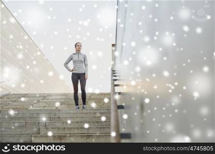 fitness, sport, people and healthy lifestyle concept - sporty woman standing on in city stairs over snow