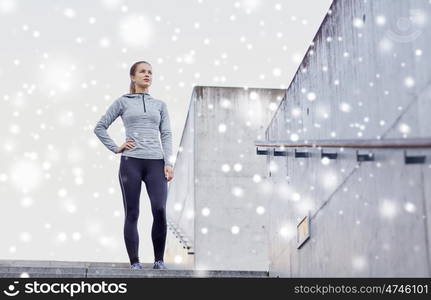 fitness, sport, people and healthy lifestyle concept - sporty woman standing on in city stairs over snow