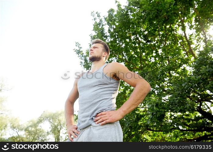 fitness, sport, people and healthy lifestyle concept - sporty young man with crossed arms at summer park