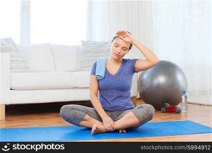 fitness, sport, people and healthy lifestyle concept - tired woman with towel after exercising on mat at home