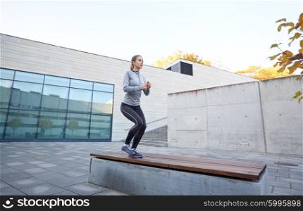 fitness, sport, people and healthy lifestyle concept - woman exercising on bench outdoors
