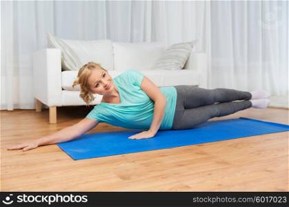 fitness, sport, people and healthy lifestyle concept - woman exercising on mat at home