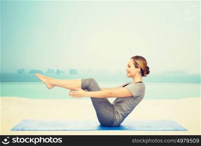 fitness, sport, people and healthy lifestyle concept - woman making yoga in half-boat pose on mat over infinity edge pool at hotel resort background. woman making yoga in half-boat pose on mat