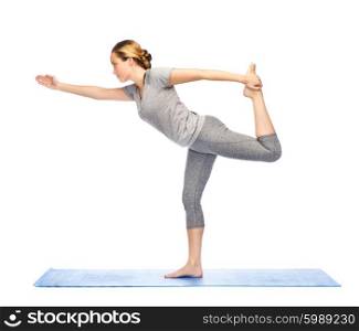 fitness, sport, people and healthy lifestyle concept - woman making yoga in lord of the dance pose on mat