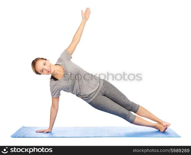 fitness, sport, people and healthy lifestyle concept - woman making yoga in side plank pose on mat