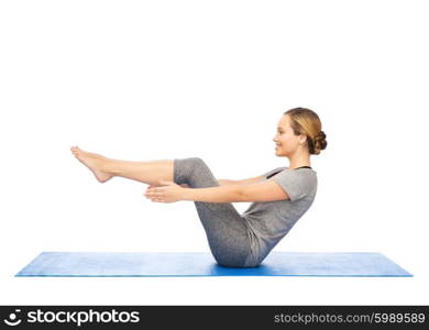 fitness, sport, people and healthy lifestyle concept - woman making yoga in half-boat pose on mat