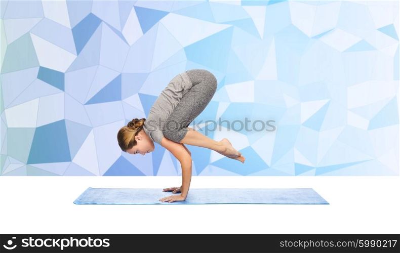 fitness, sport, people and healthy lifestyle concept - woman making yoga in crane pose on mat over blue polygonal background
