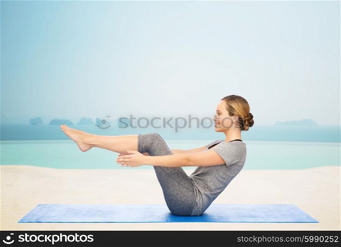 fitness, sport, people and healthy lifestyle concept - woman making yoga in half-boat pose on mat over infinity edge pool at hotel resort background