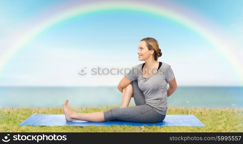 fitness, sport, people and healthy lifestyle concept - woman making yoga in twist pose on mat over blue sky, rainbow and sea background