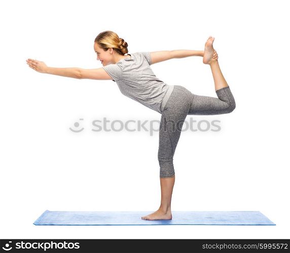 fitness, sport, people and healthy lifestyle concept - woman making yoga in lord of the dance pose on mat