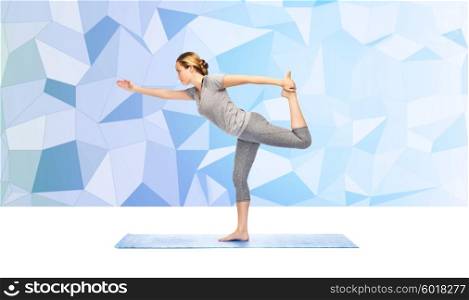 fitness, sport, people and healthy lifestyle concept - woman making yoga in lord of the dance pose on mat over blue polygonal background
