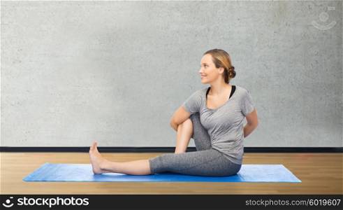 fitness, sport, people and healthy lifestyle concept - woman making yoga in twist pose on mat over room or gym background
