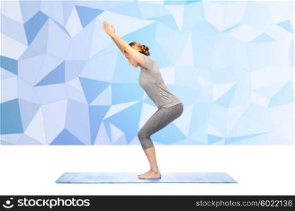 fitness, sport, people and healthy lifestyle concept - woman making yoga in chair pose on mat over low poly background