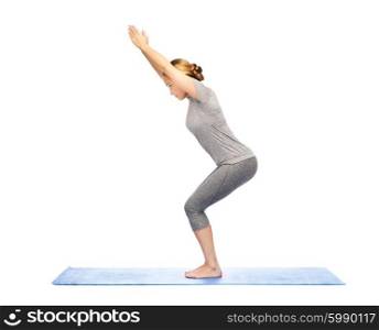 fitness, sport, people and healthy lifestyle concept - woman making yoga in chair pose on mat