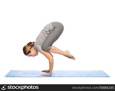 fitness, sport, people and healthy lifestyle concept - woman making yoga in crane pose on mat